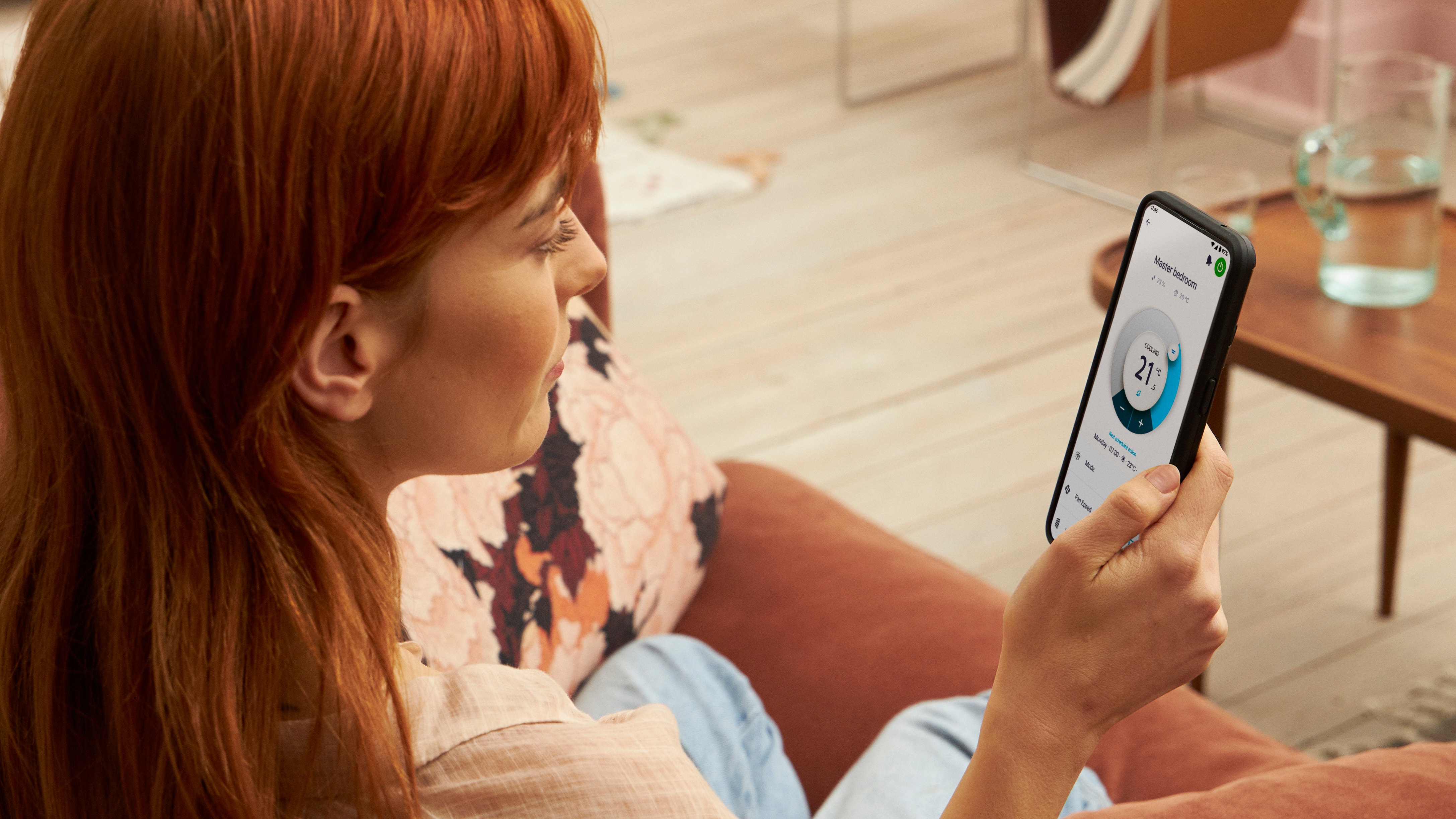 En kvinde bruger en app til at betjene sin opvarmningsløsning. En kvinde bruger en app til at betjene sin opvarmningsløsning.